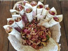 an arrangement of dried flowers in a wicker basket on a wooden table with lace