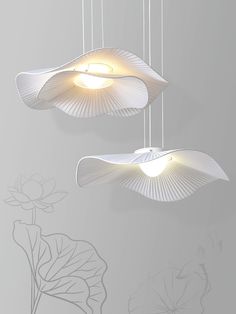 two white lamps hanging from the ceiling in front of a wall with lotus leaves on it