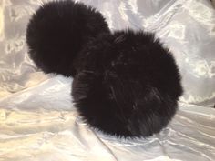 two black furry balls sitting on top of a white sheet