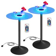 two round tables with remote controls on each side and blue lights at the top, along with an illuminated flower centerpiece