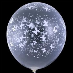 a clear balloon with white butterflies and swirls on the outside, against a black background