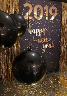 balloons and streamers in front of a new year's eve backdrop with gold confetti