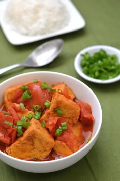 a white bowl filled with tofu and vegetables on top of a green table cloth