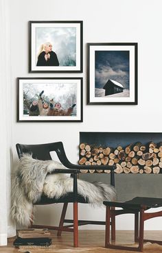 a living room with pictures on the wall and a chair next to a firewood log