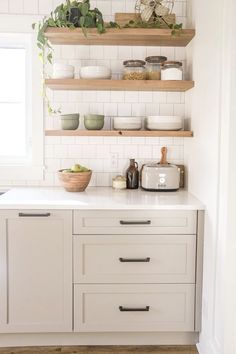 a white kitchen with open shelving above the sink and dishes on the counter top