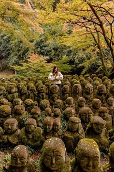 a woman standing in the middle of a field full of heads made out of moss