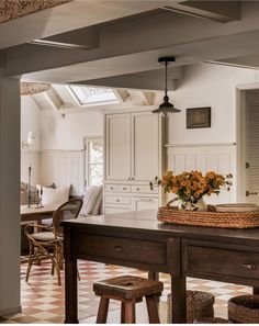 a kitchen table with flowers in a basket sitting on it's top and chairs around it