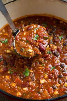 a spoon full of chili and beans in a bowl