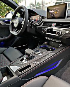 the interior of a modern car with leather and blue trims, including steering wheel controls