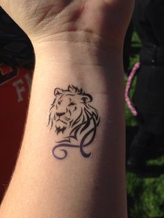 a small tattoo on the wrist of a person with a lion head in black ink