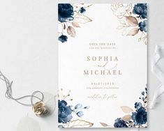 wedding save the date card with blue flowers and gold foil on it, next to white ribbon