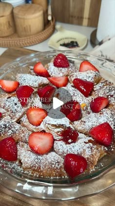 a cake with powdered sugar and strawberries on top is sitting on a table