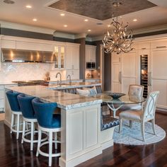 a large kitchen with an island in the middle and blue chairs at the countertop