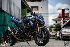 a blue and black motorcycle parked on the side of a road next to a building