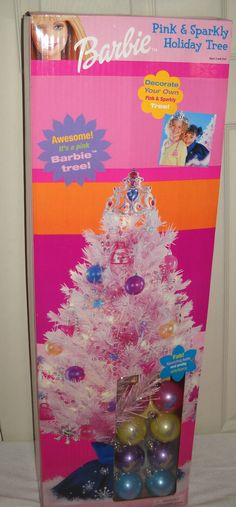 a pink and sparky christmas tree with ornaments in it's display case on a table