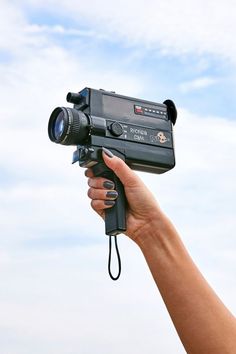 a hand holding a video camera up to the sky