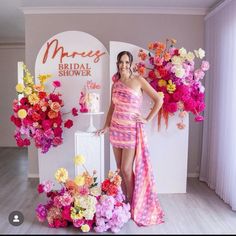 a woman in a pink dress standing next to a flower display with flowers on it