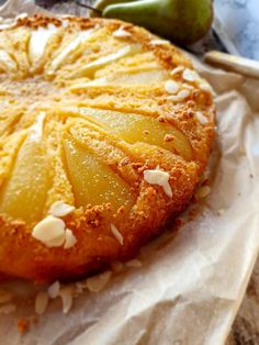 a pineapple upside down cake sitting on top of a piece of wax paper next to an apple