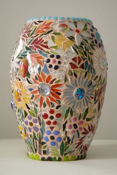 a multicolored vase sitting on top of a white table next to a wall