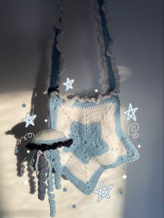 a crocheted bag hanging from a hook on a wall with stars around it