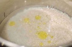 rice and oil are mixed together in a large pot on the stove top, with little yellow dots