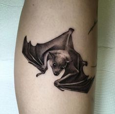 a black and white photo of a bat tattoo on the right thigh, it appears to be flying through the air