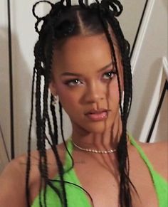 a woman with very long hair wearing a green top and braids on her head