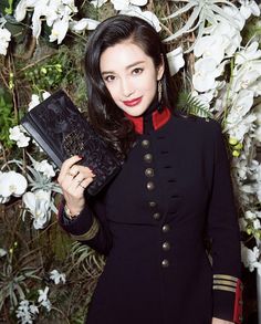 a woman holding a book in front of flowers