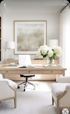 a home office with white furniture and flowers on the desk