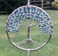 a silver tree of life with blue and green crystals hanging from it's center