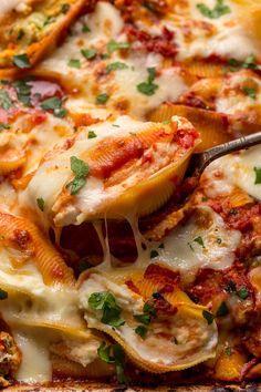 a close up of a plate of food with cheese and sauce on it, being held by a fork