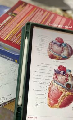 an open book with diagrams of the human heart on it and other medical equipment nearby