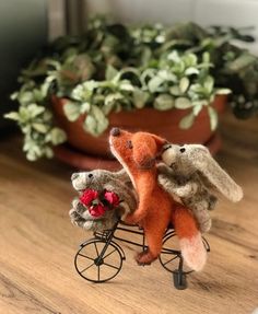 two stuffed animals are riding on a miniature bicycle