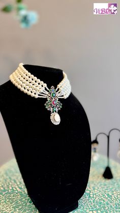 Indulge in luxury with our elegant Pearl 5-Line Choker set. Adorned with ruby emeralds, sapphires, and ADs, this pendant and earring set adds a sophisticated touch to any outfit. Its versatility allows it to be worn with various ensembles, exuding a regal charm. Elevate your style with this exclusive set. Fancy Clutch, Kids Wear Boys, Pendant And Earring Set, Bangle Box, Kids Wear Girls, Silk Saree Banarasi, Block Print Saree, Fancy Gowns, Silk Thread Bangles