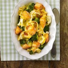 a white bowl filled with pasta and broccoli on top of a checkered table cloth