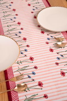 the table is set with silverware and flowers on pink striped placemats, along with two gold - plated utensils