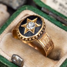 This delightful circa late-Victorian era ring is accented with one (1) old mine cut diamond bead set into a star shaped setting and bordered with black enamel. The top face of the shank is accented with engraved details. The ring measures 11.1mm at the top, rises 3.0mm above the finger, tapering to 4.1mm wide and 0.3mm thick at the base of the shank. This ring is currently a size 3.25. This ring shows some overall wear and we left it unpolished with a beautiful natural patina. Antique Rings Art Deco, Antique Cocktail Ring, Victorian Diamond Ring, Victorian Engagement Rings, Star Motif, Old Mine Cut Diamond, Wax Carving, Art Deco Diamond Rings, Punk Vintage