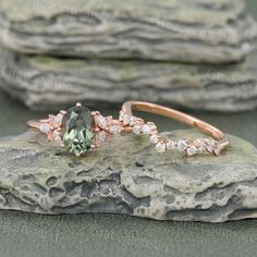 an engagement ring with a green and white diamond in the middle on top of a rock