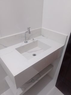 a white bathroom sink sitting next to a wall mounted faucet under a mirror