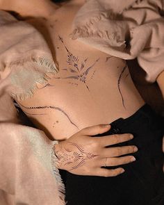 a woman's stomach with tattoos on it and her hand resting on the belly