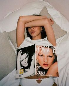 a woman laying in bed with two magazines