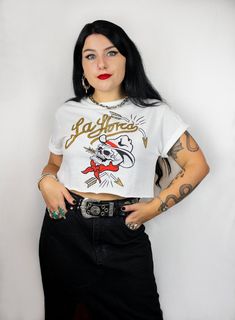 White crop T-shirt with gothic western design of a cowboy's skull and the text "La Horca". Screen-printed in black, red and gold metallic effect. Size reference Height: 1'48m - Size S We advise you to choose your usual size. If you have any doubts about the size you can contact us. Composition and care 100% cotton. Machine wash at 40o maximum. Do not bleach. Tumble dry. Iron at low temperature. Do not dry clean. It is recommended to wash inside out to extend the life of the print. Goth Western Aesthetic, Gothic Cowgirl, Gothic Western, Goth Cowboy, Aesthetic Cowgirl, Bat Shirt, Goth Shirt, Style Gothic, Dark Style