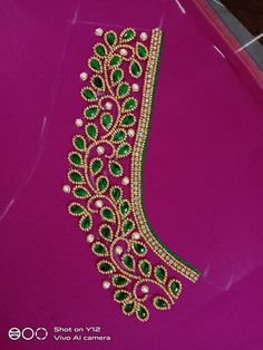 the green and white beaded bracelet is displayed on a pink surface with other jewelry items