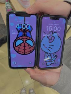 two people holding up their cell phones with cartoon characters on them