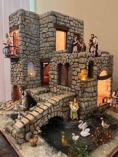 a miniature castle with figurines on top of it and water in the middle