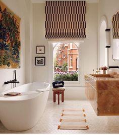 a bath room with a large tub next to a window and a painting on the wall