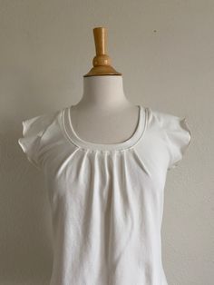 Womens short sleeve tshirt. This is a cute little tee with raglan cap sleeves. It has pleats in front with a scoop neck. It is loose and flowy and is made with my favorite soft stretchy cotton jersey knit.  Length from shoulder to hem size Small is 24", length increases 1/2" each size up (note the length can be adjusted as needed) Shown in Off White See Swatch Chart in the last photo for available Color options. Garments are Made To Order Please allow 7-10 days for your item to be sewn Below are my standard size measurements, which are simply a guideline, if you would like to include your personal measurements in the notes to seller box during checkout, I will be sure to make you the best fit ~ if you have any questions feel free to ask :)  BASIC SIZING   XSmall 0-2 Bust 33-34, Waist 25-26 Loose Fit Shirts, Scoop Neck Top, Knitted Tshirt, Caps For Women, Jersey Tee, Short Sleeve Blouse, Cotton Knit, Cap Sleeve, Stretch Cotton