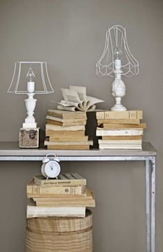 some books are stacked on top of each other in front of a table with a lamp