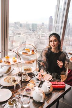 a woman sitting at a table in front of a window with desserts on it