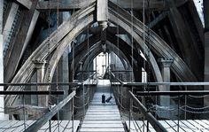 a man is walking across a bridge with chains